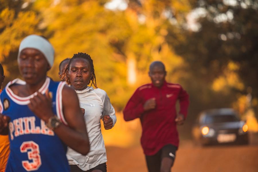 Runners on the road as a car passes