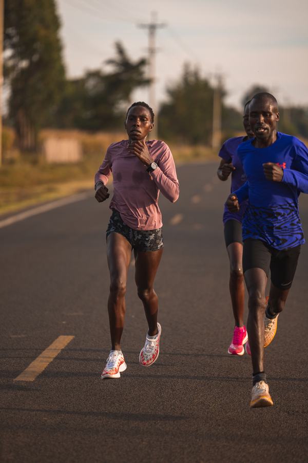 Two athletes running the tarmac road