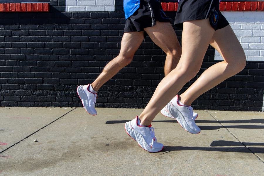 Runners mid-stride against a black brick wall