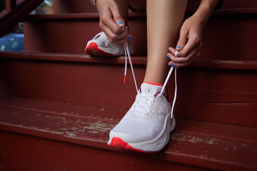 Lacing a white race shoe on red stairs
