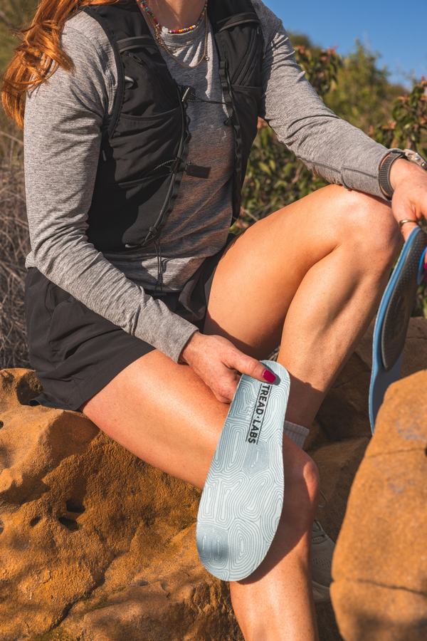Holding the insole, sat on a rock