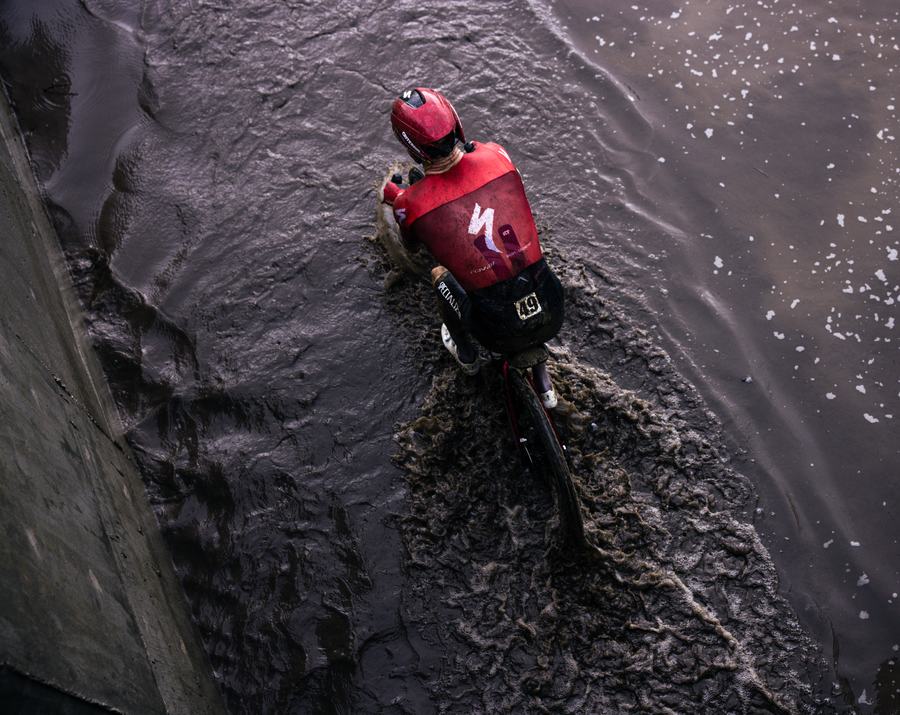 Rider crossing a field of black mud, from above